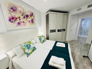 Un dormitorio con una cama blanca y un cuadro en la pared. en Marina Bay 1, en Benalmádena