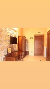 a room with a desk and a tv and a stone wall at La fattoria di Carlotta in Maenza