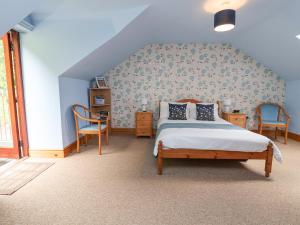 a bedroom with a bed and two chairs at Henblas Cottage in Abergele
