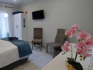 a bedroom with a bed and two chairs and a table with flowers at Lodge Azure in Port Edward