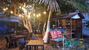 a restaurant with tables and chairs and a palm tree at Hospedaje Kairos Capurgana in Capurganá