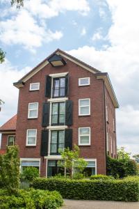 a red brick building with white windows and bushes at De Mölle in Winterswijk