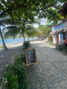 a chalkboard sign sitting on a sidewalk next to a beach at Hospedaje Kairos Capurgana in Capurganá