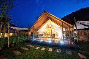 een huis met een tent in een tuin 's nachts bij Herbal Glamping Resort Ljubno in Ljubno