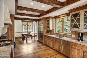 a kitchen with wooden cabinets and a dining room with a table at 5BR Alpine Luxury Home with Private Hot Tub in Vail +32 photos
