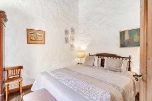a white bedroom with a bed and a chair at Casa Montesdeoca - Jacaranda in Las Palmas de Gran Canaria
