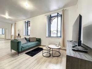 a living room with a green couch and a tv at Charmant Duplex au Cœur Vosgien in Charmes