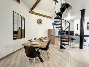 a dining room with a table and a spiral staircase at Charmant Duplex au Cœur Vosgien in Charmes +7 photos