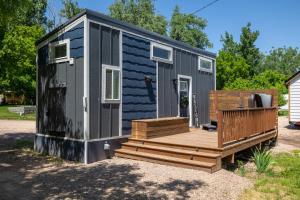 a blue and gray tiny house with a wooden deck at Creekside Village Inn in Spearfish