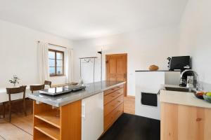 a kitchen with white walls and wooden cabinets and a counter top at Ansitz Baumannhof Apt Erker Suite in Falzes +27 photos
