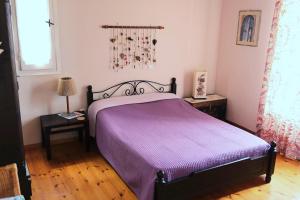 a bedroom with a purple bed and a window at Vereniki Andros guesthouse in Batsi