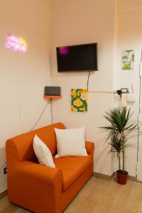 an orange couch in a living room with a tv at Sunshine Apartment - Salerno in Salerno