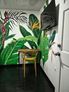 une table et une chaise dans une chambre avec une fresque murale dans l'établissement Habitaciones Smith, à San José