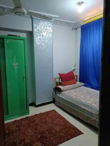 a bedroom with two beds and a green door at شقة مفروشة بالرضوان حي العقاد باسوان in Shellal