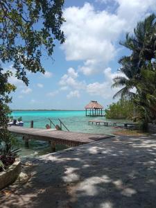 a dock on a beach with a gazebo in the water at Casa Piedra de Agua Bacalar in Bacalar