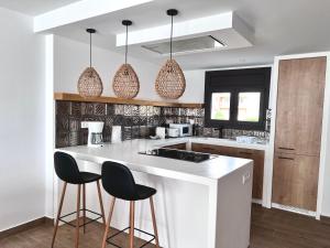 a kitchen with a white counter and two bar stools at Casa LARA in Empuriabrava