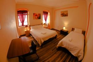 a room with two beds and a table and a desk at Vibes Aurik in Quito