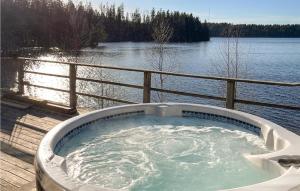a hot tub on a deck next to a body of water at Amazing Home In Dalsjöfors With Sauna in Dalsjöfors
