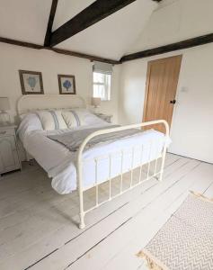 une chambre avec un lit blanc dans une pièce dans l'établissement Lobster Pot Cottage, à Fulmodeston
