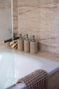 une salle de bain avec trois bouteilles de savon dans une baignoire dans l'établissement El Rinconcito, à Torre de Benagalbón