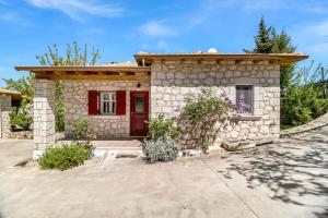a small stone house with a red door at Apanema Mindfulness Resort Lefkada - ultra fast Starlink WiFi in 2025 in Asprogerakata
