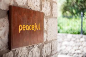 a metal sign on a stone wall with the word peoria at Apanema Mindfulness Resort Lefkada - ultra fast Starlink WiFi in 2025 in Asprogerakata