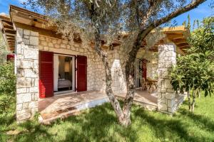 a stone house with red doors and a tree at Apanema Mindfulness Resort Lefkada - ultra fast Starlink WiFi in 2025 in Asprogerakata