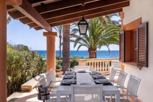 a dining table and chairs on a patio with the ocean at Schönes Haus mit Pool direkt am Meer in Costa des Pins
