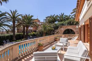 a balcony with chairs and tables and palm trees at Schönes Haus mit Pool direkt am Meer in Costa des Pins