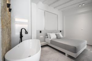 a white bedroom with a bed and a bath tub at Astrum Luxury Suites in Vourvourou