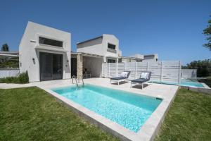 a villa with a swimming pool in front of a house at Astrum Luxury Suites in Vourvourou