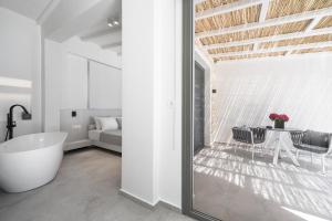 a bathroom with a tub and a table and a bed at Astrum Luxury Suites in Vourvourou