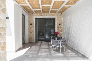 a porch with a bench and a table with flowers on it at Astrum Luxury Suites in Vourvourou