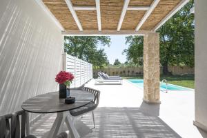 a patio with a table and chairs and a pool at Astrum Luxury Suites in Vourvourou