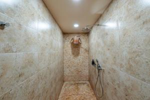 a bathroom with a shower with a stone wall at Pensiunea Eden Garden Smida in Smida