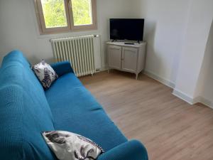 a blue couch in a living room with a television at La Clef du Bonheur Maison de vacances entre Loire et Vignobles in Herry