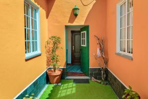 an orange house with a green door and a plant at Casa dos Castanheiros Angra do Heroismo in Terra Chã