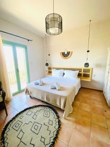 a bedroom with a large white bed and a rug at Joyanna Villa Pool, Sea View & Olive Grove Serenity in Mani in Kalívia