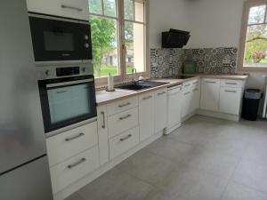 a kitchen with white cabinets and a sink and a window at La Clef du Bonheur Maison de vacances entre Loire et Vignobles in Herry