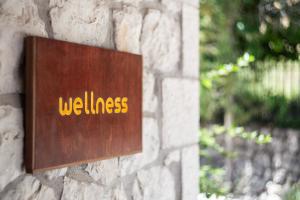 a sign on a stone wall with the word wellness at Apanema Mindfulness Resort Lefkada - ultra fast Starlink WiFi in 2025 in Asprogerakata
