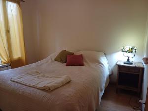a bedroom with a white bed with a red pillow at De la Villa de Rada Tilly in Rada Tilly