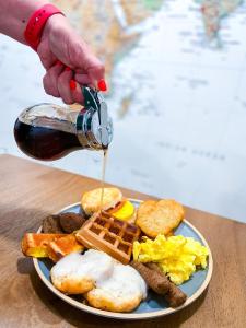 a person pouring syrup onto a plate of breakfast food at PINEMARK Inn Suites Events in Saint Clair