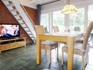 a dining room with a table and chairs and a tv at Ferienhaus Cosima mit schönem Garten in Anjum