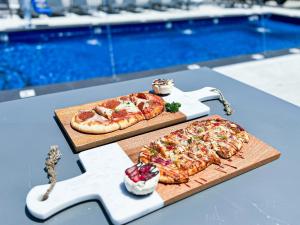 two pizzas on cutting boards on a table near a pool at PINEMARK Inn Suites Events in Saint Clair