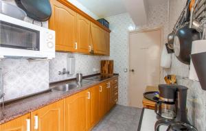 a kitchen with wooden cabinets and a sink and a microwave at Beautiful Apartment In Santa Pola in Santa Pola