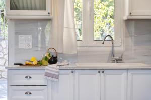 a kitchen with white cabinets and a sink at Apanema Mindfulness Resort Lefkada - ultra fast Starlink WiFi in 2025 in Asprogerakata