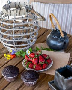 a table with cupcakes and a plate of strawberries and a basket at Apanema Mindfulness Resort Lefkada - ultra fast Starlink WiFi in 2025 in Asprogerakata