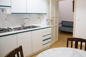 a kitchen with white cabinets and a sink and a table at Honoré de Balzac in Alghero
