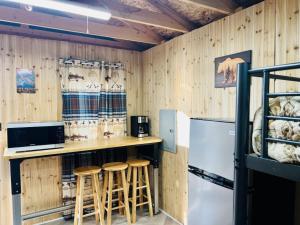 a kitchen with a counter with stools and a refrigerator at Grayling Bunkhouse at Red-Bow in Sterling