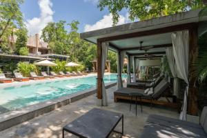 een buitenterras met een zwembad en een bed en stoelen bij Arthouse Tulum Iconic Apartment Beach Club Access in Tulum